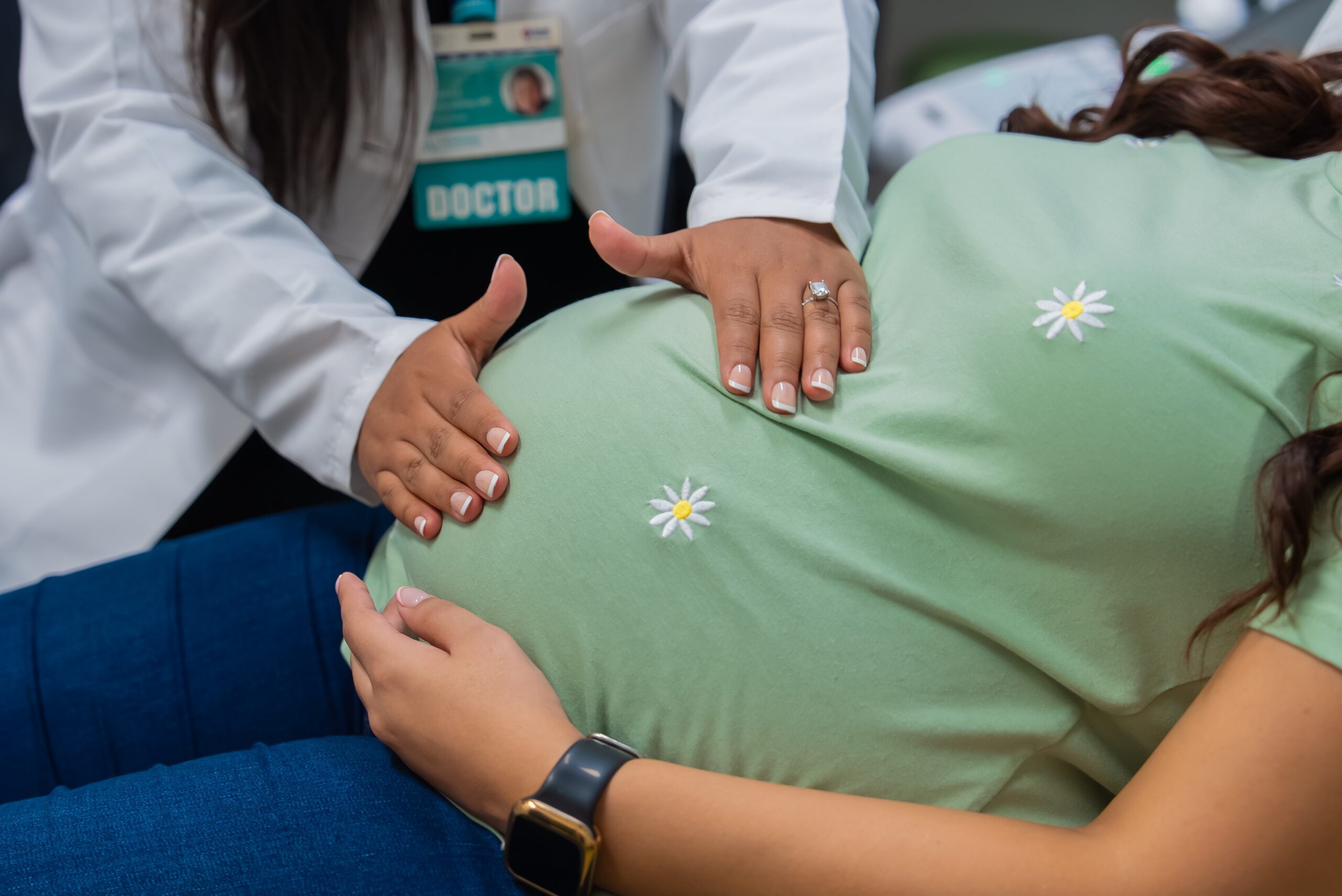 Maternal fetal medicine specialist checks pregnant woman's belly for growth and position of baby.