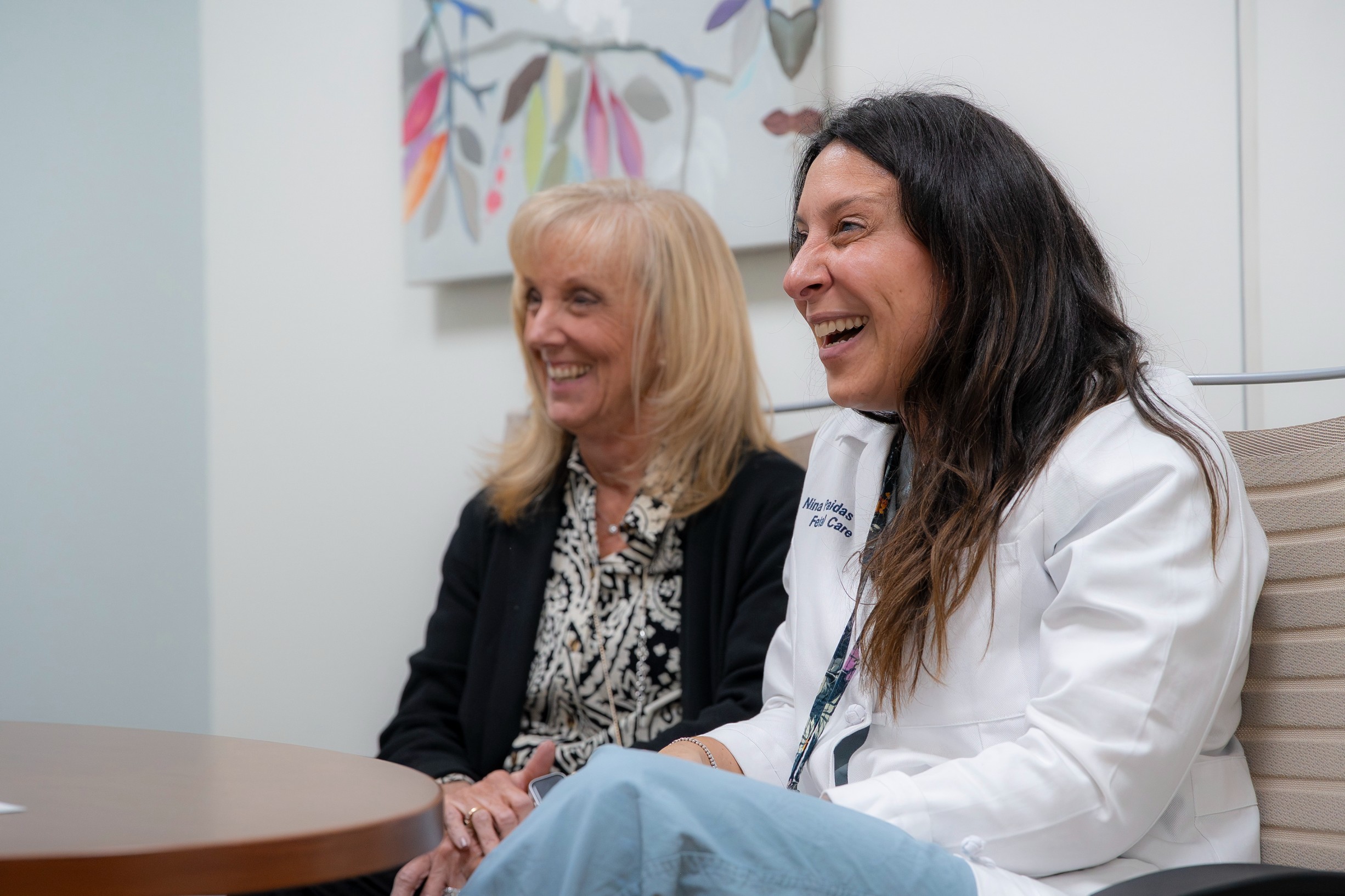 Maternal fetal care specialists sitting at a table and smiling as they meet with their patient.