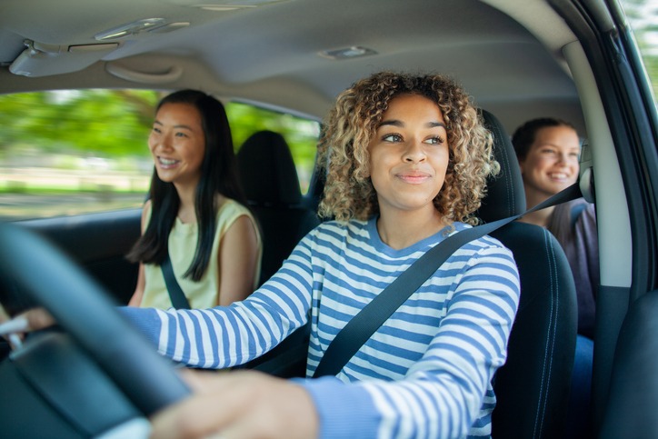 Healthy teens driving in a car with seat belts on.