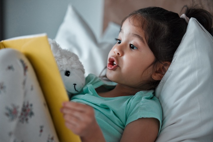 Girl reading story before bed while avoiding screens and bright lights