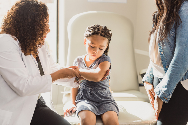 A pediatrician checks a young girls arm for a rash typical of eczema or atopic dermatitis