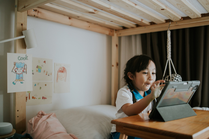 Young child using a tablet independently at home, representing screen-based learning and technology use in early childhood